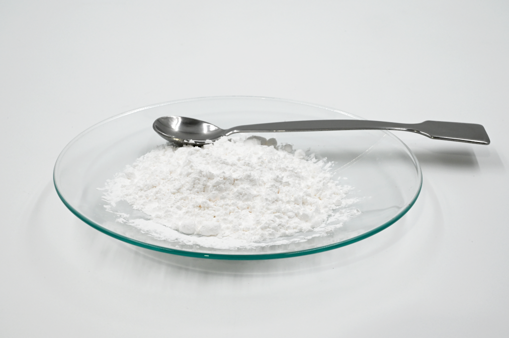 White drying agent powder on a watch glass with a spoon spatula