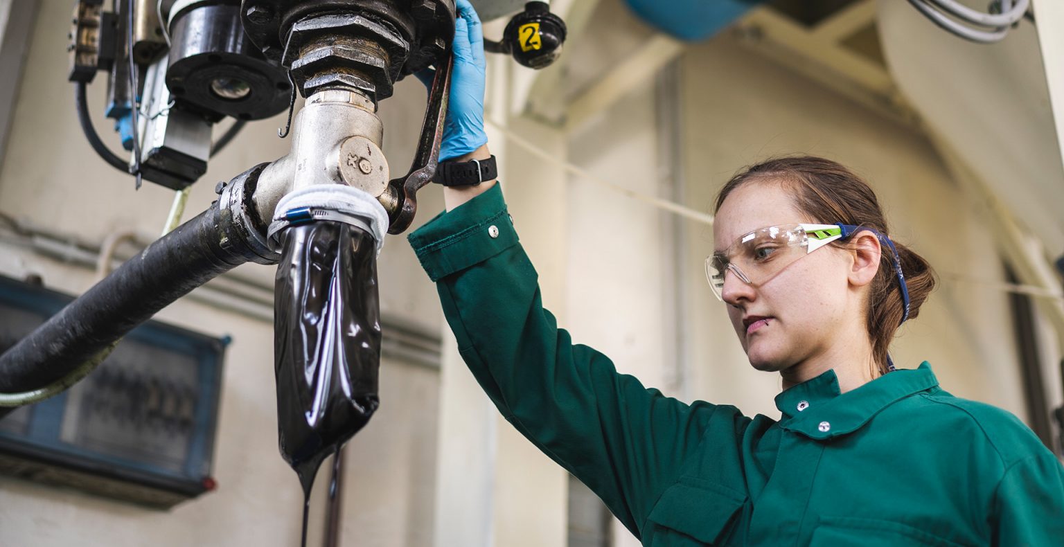 Produktionsmitarbeiterin bei der Filtration von schwarzen Gießharz für Elektronik