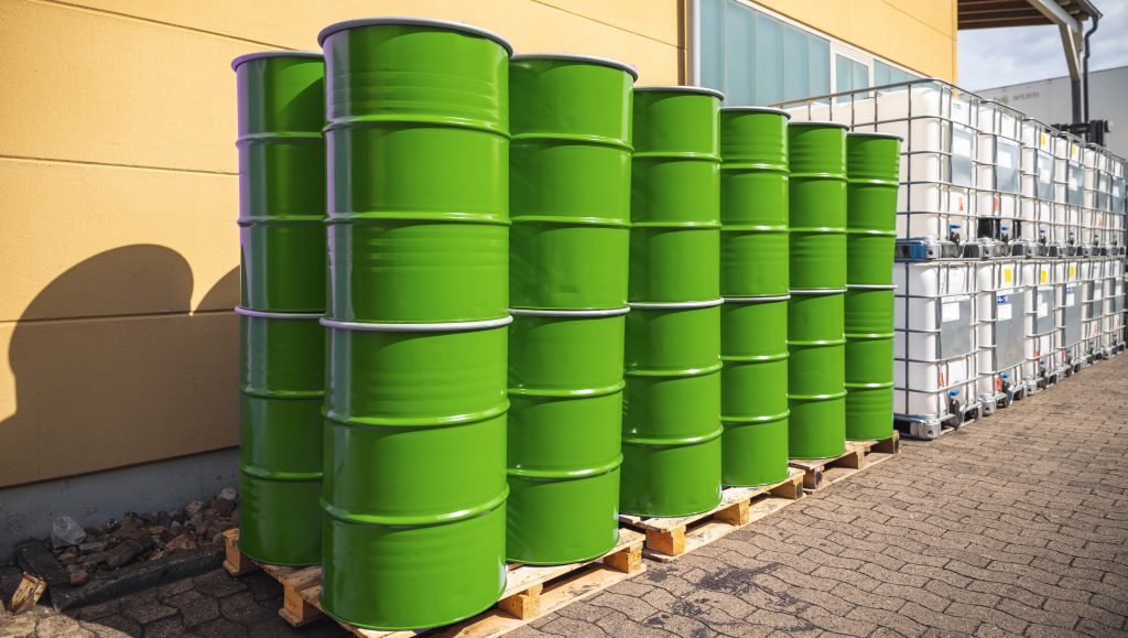 Green barrels in front of a yellow wall.