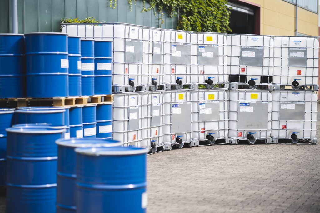 Blue barrels and IBCs in front of a hall