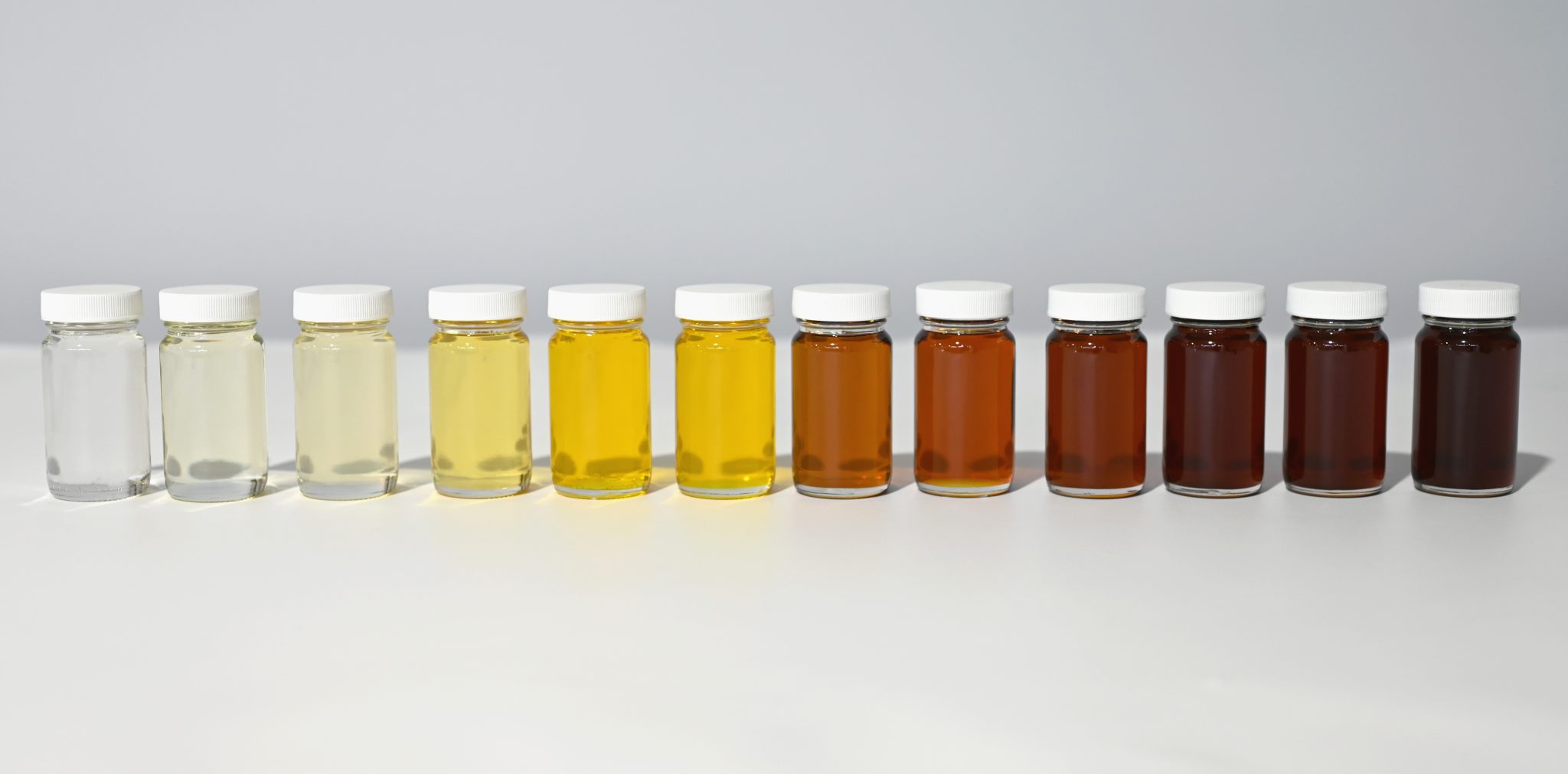 Transparente Gläser, gefüllt mit verschiedenen Isocyanaten; von transparent über gelb bis braun.