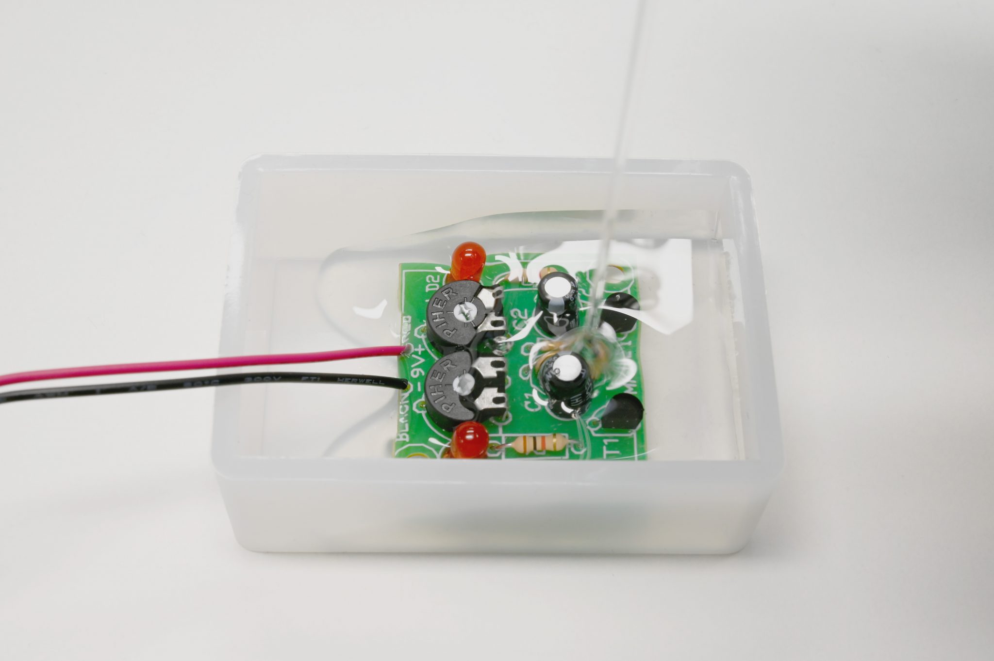 Potting of transparent ISO-POX CC500 onto a green circuit board with red LED lights.